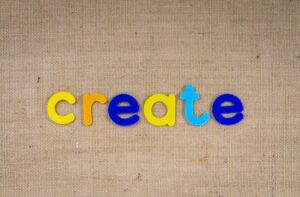 Colorful felt letters spelling 'create' on a burlap background, capturing creativity concept.