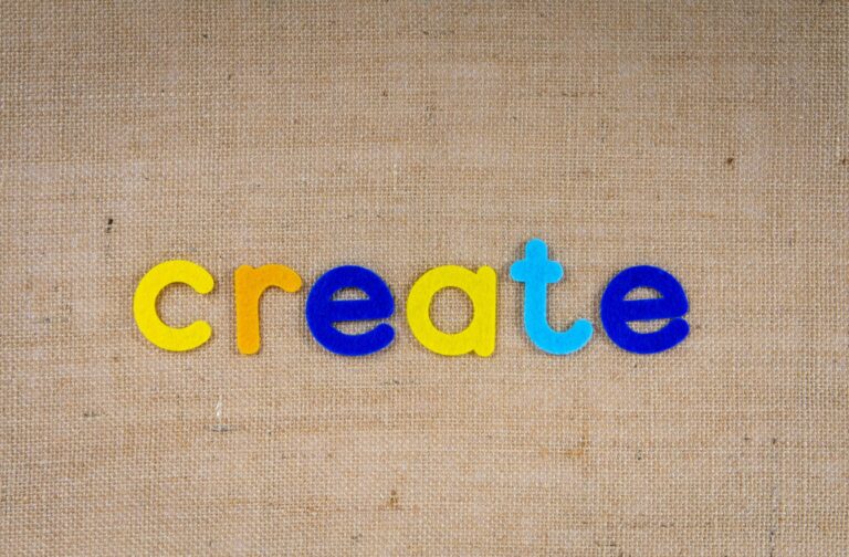 Colorful felt letters spelling 'create' on a burlap background, capturing creativity concept.